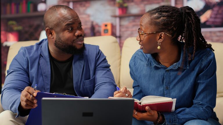 Black man and woman writing a report with information from notebook